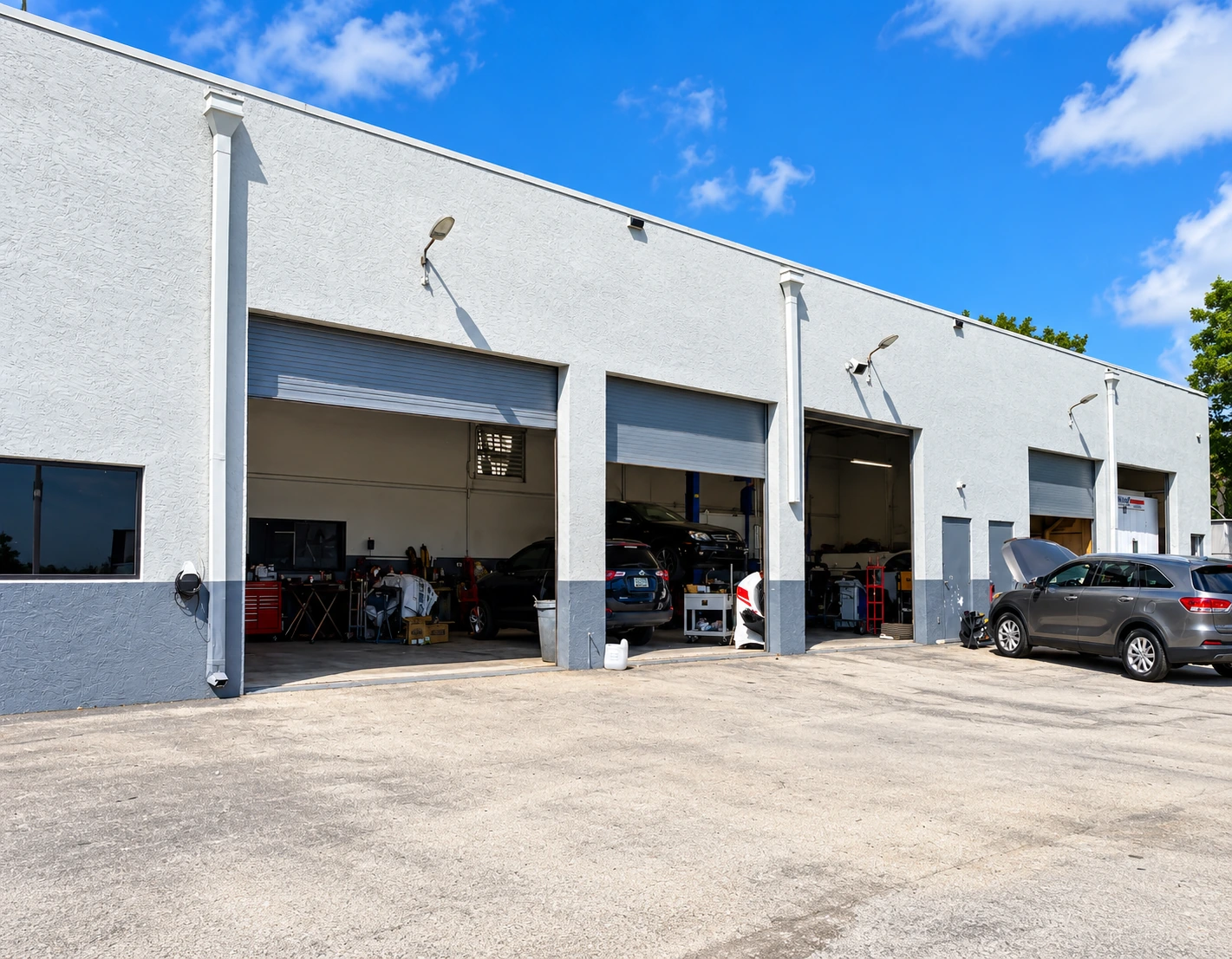 Open repair bays at G&G Auto Collision, with vehicles inside the workshop.